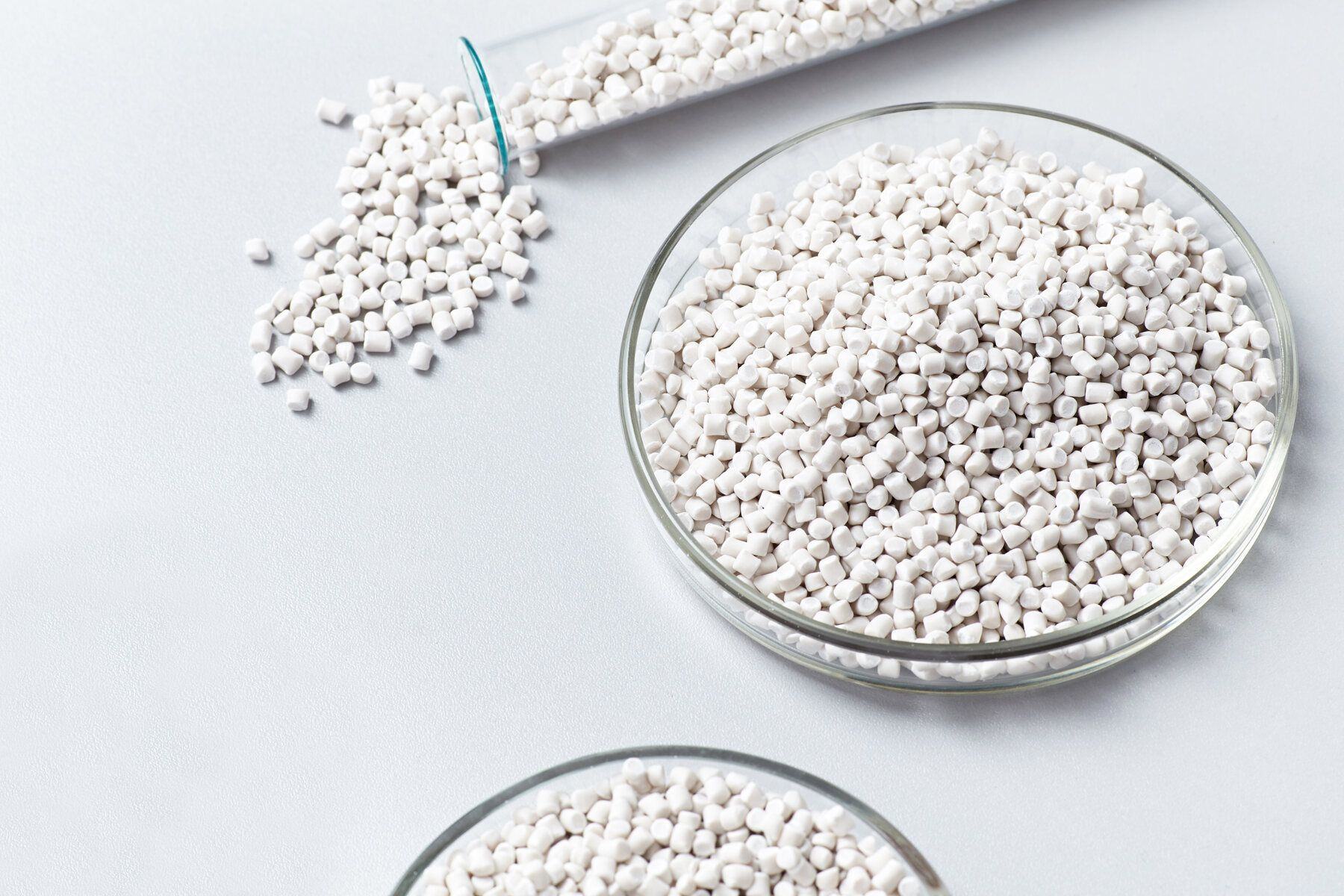 Hvide komposterbare PLA-pellets i petriskåle og glasbeaker